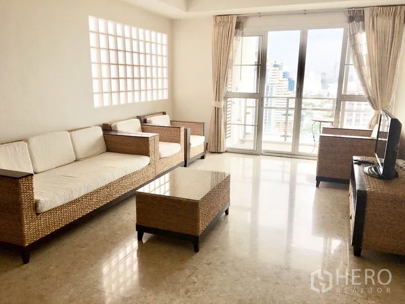 公寓 出租在Khlong Toei, Bangkok - 阳光客厅，藤编沙发，阳台门通向城市景观。