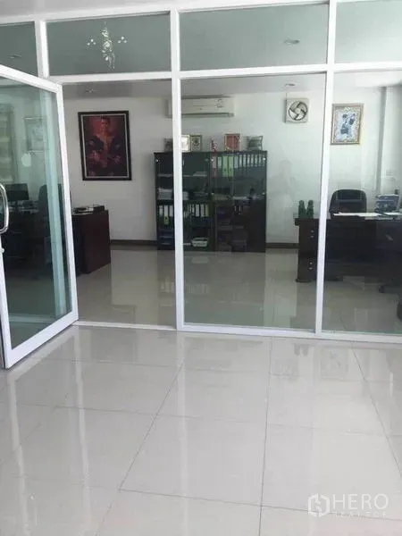 Factory for rent or sale in Samut Prakan - Bright tiled office area with glass partition walls and sliding doors inside the factory.