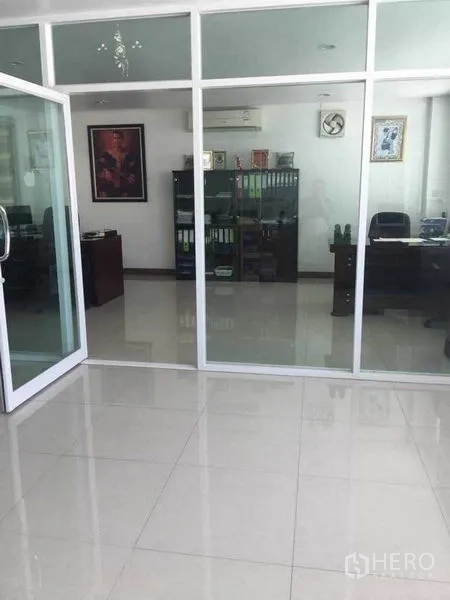 Factory for rent or sale in Samut Prakan - Bright tiled office area with glass partition walls and sliding doors inside the factory.