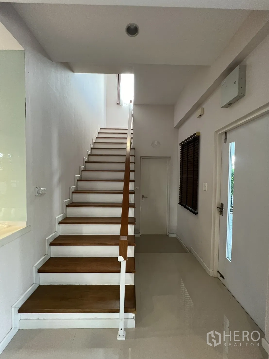 Detached House for rent in Bang Kapi, Bangkok - Entrance hall with wooden staircase, high ceiling, and glossy floors.