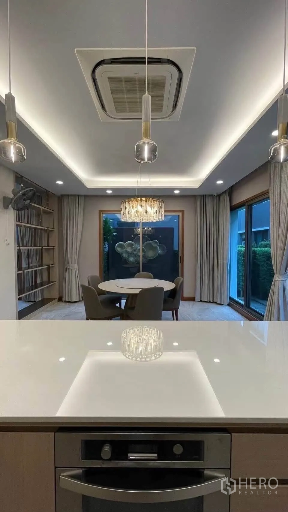 Detached House for rent in Prawet, Bangkok - Dining area with round table, chandelier, sliding doors and pantry island.