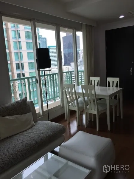 Condominium for rent in Pathum Wan, Bangkok - Open living–dining space with floor-to-ceiling windows and balcony facing nearby towers.