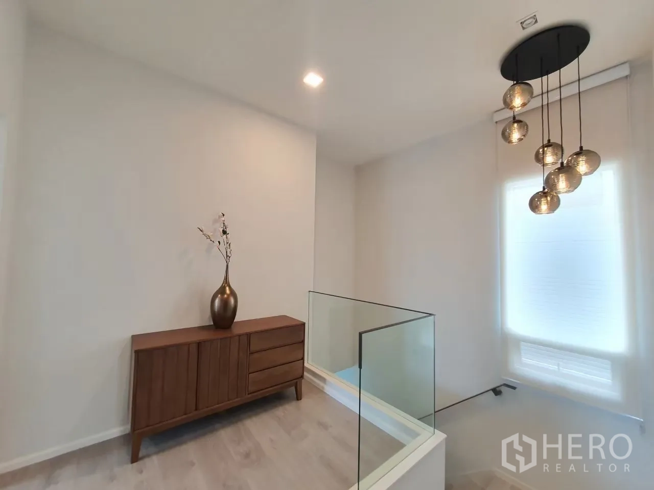 独立式住宅 出租在Prawet, Bangkok - 楼梯平台，玻璃扶手与吊灯装饰。