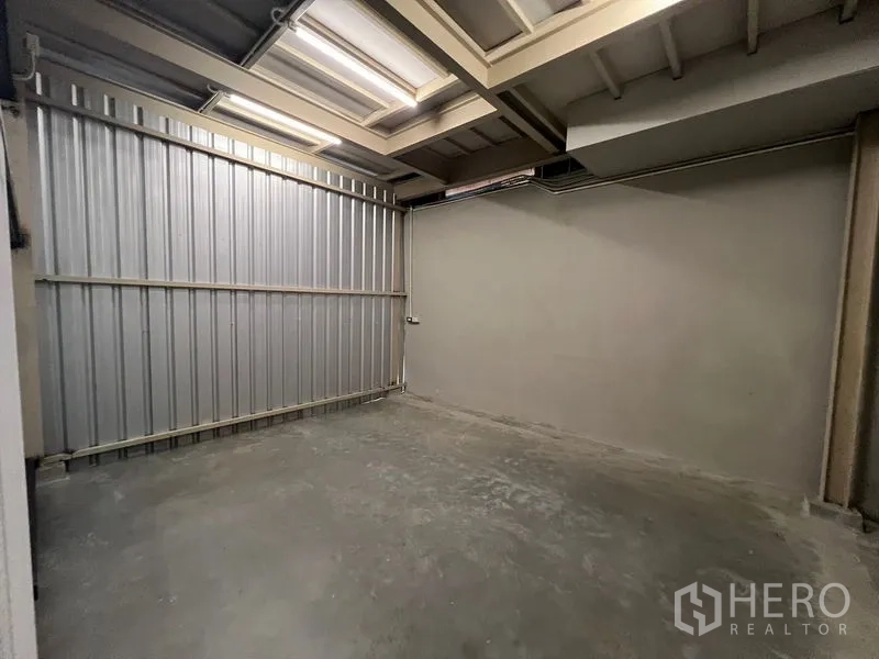 Warehouse for rent in Prawet, Bangkok - Covered storage or loading bay with metal cladding and concrete floor.