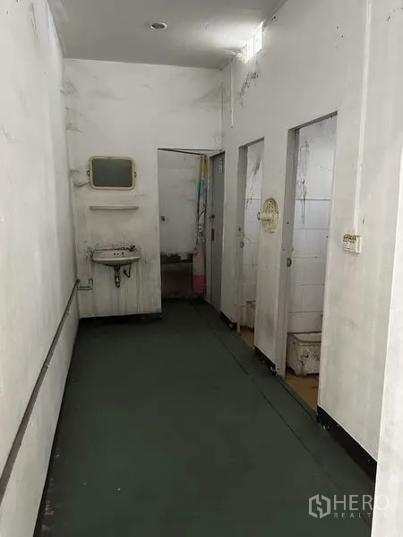 Factory for rent in Bang Bua Thong, Nonthaburi - Corridor to restroom area with sink and stall doors inside the facility.