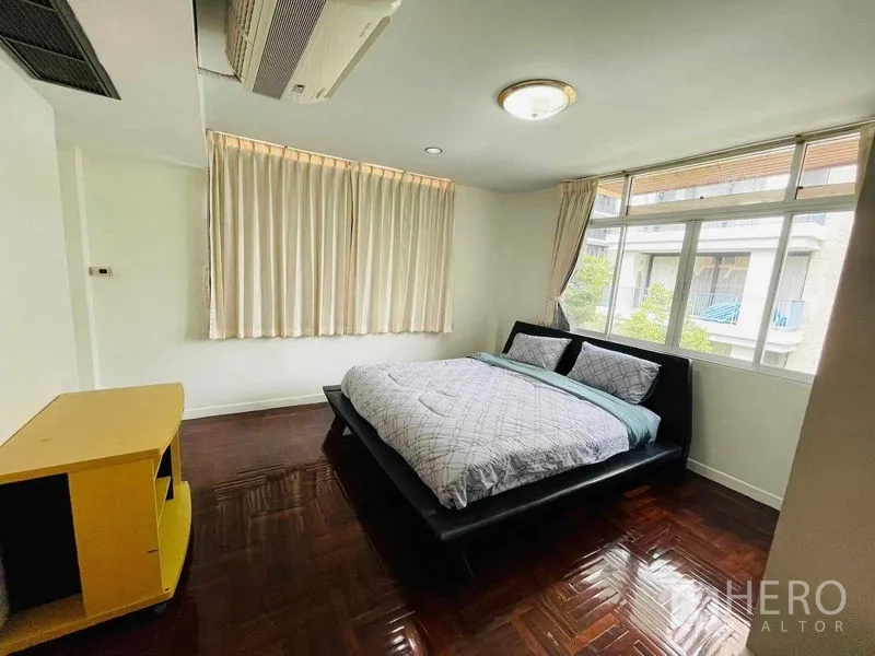 独立式住宅 出租在Watthana, Bangkok - 次卧，大窗、窗帘与深色木地板。