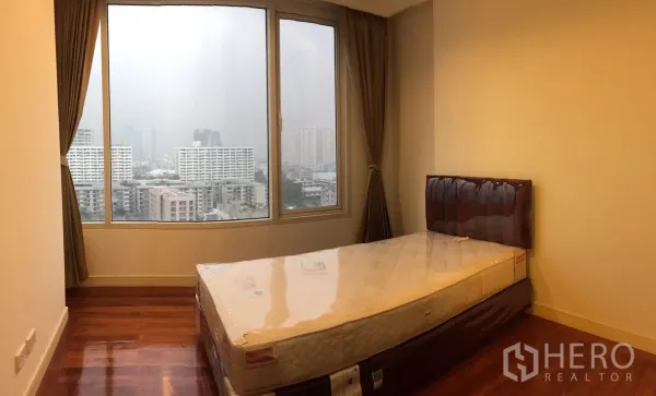 Condominium for rent in Watthana, Bangkok - Cozy bedroom with hardwood floors, single bed and wide window overlooking Bangkok skyline.