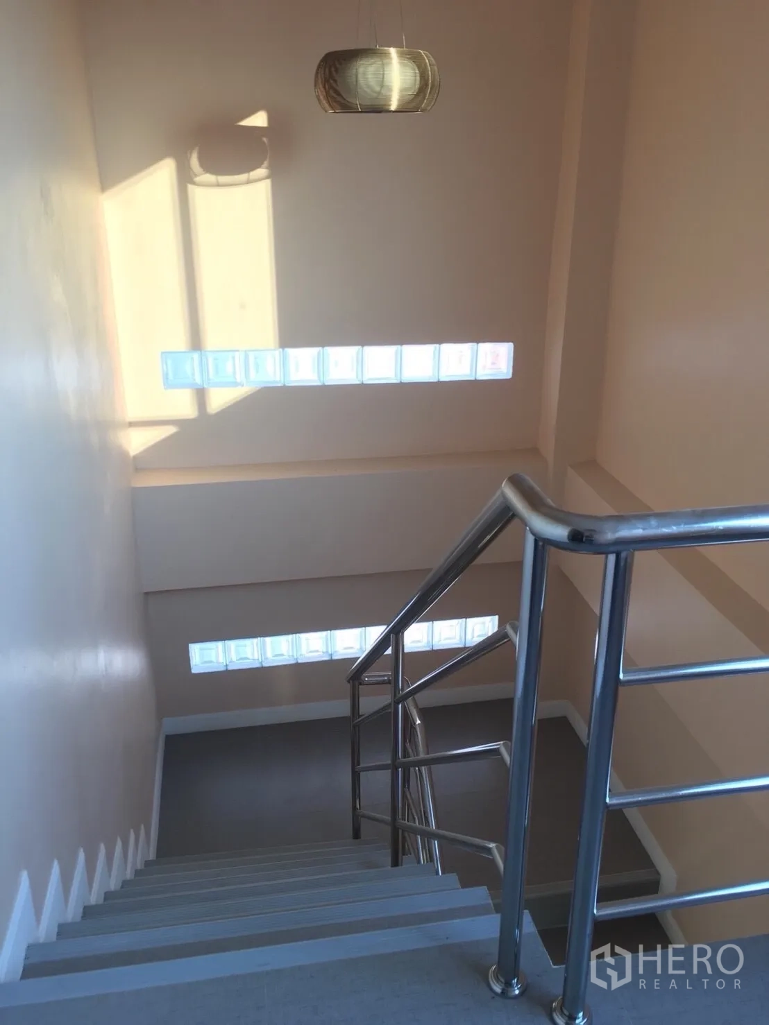 Townhouse for rent in Huai Khwang, Bangkok - Staircase with stainless-steel handrail, high ceiling and glass block windows.