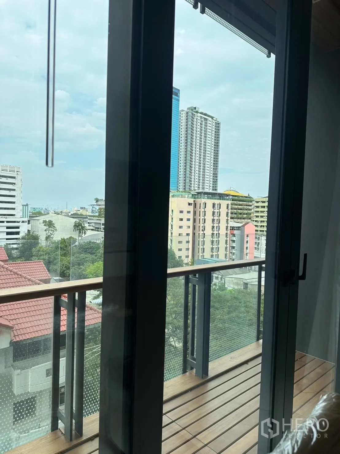 คอนโด for rent or sale in Watthana, Bangkok - ประตูระเบียงเปิดสู่วิวเมืองเหนือหลังคาและตึกสูง.