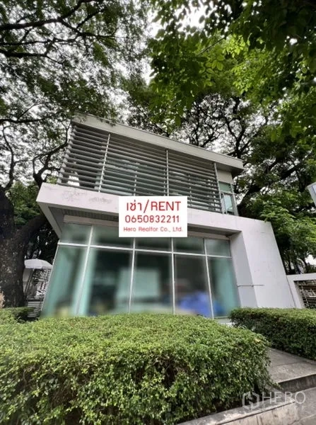 办公空间 出租在Khlong Toei, Bangkok - 白色两层独栋办公楼斜角视图，大片玻璃幕墙与修剪整齐的绿篱，树木成荫。