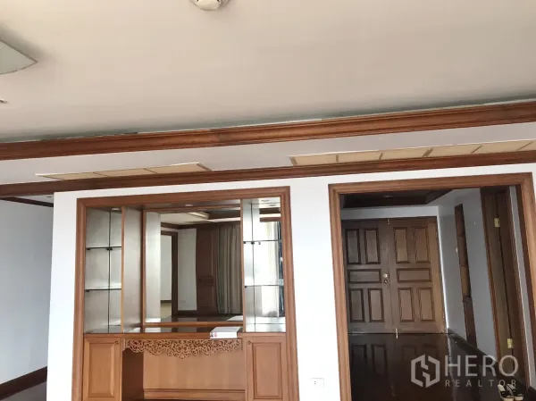 Condominium for rent in Pathum Wan, Bangkok - Entry foyer with built-in wooden cabinetry, mirrored shelves, and double wooden doors.