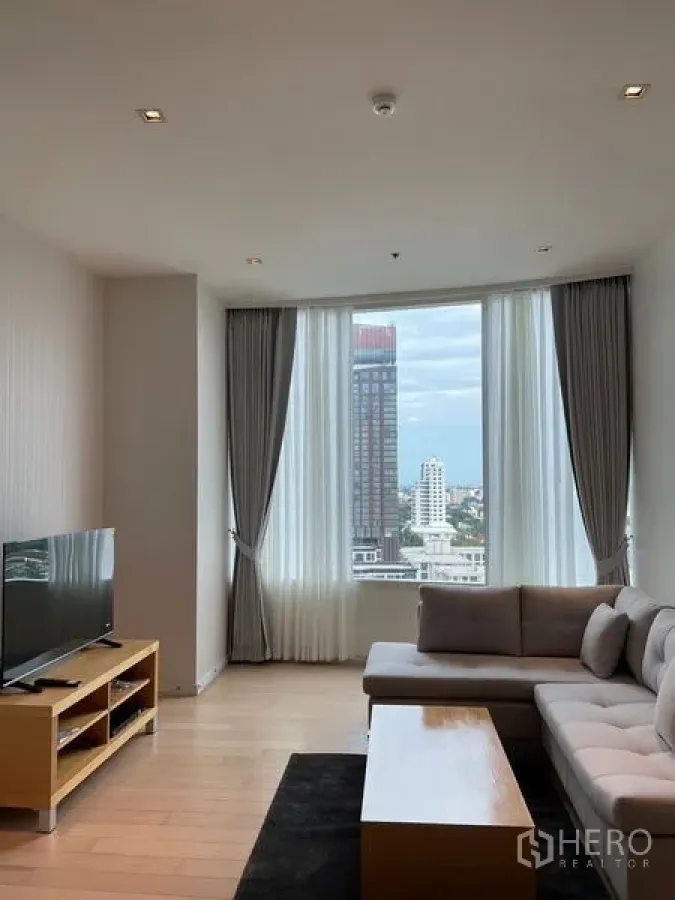 公寓 出租在Watthana, Bangkok - 客厅配沙发与电视柜，落地大窗眺望曼谷景色。