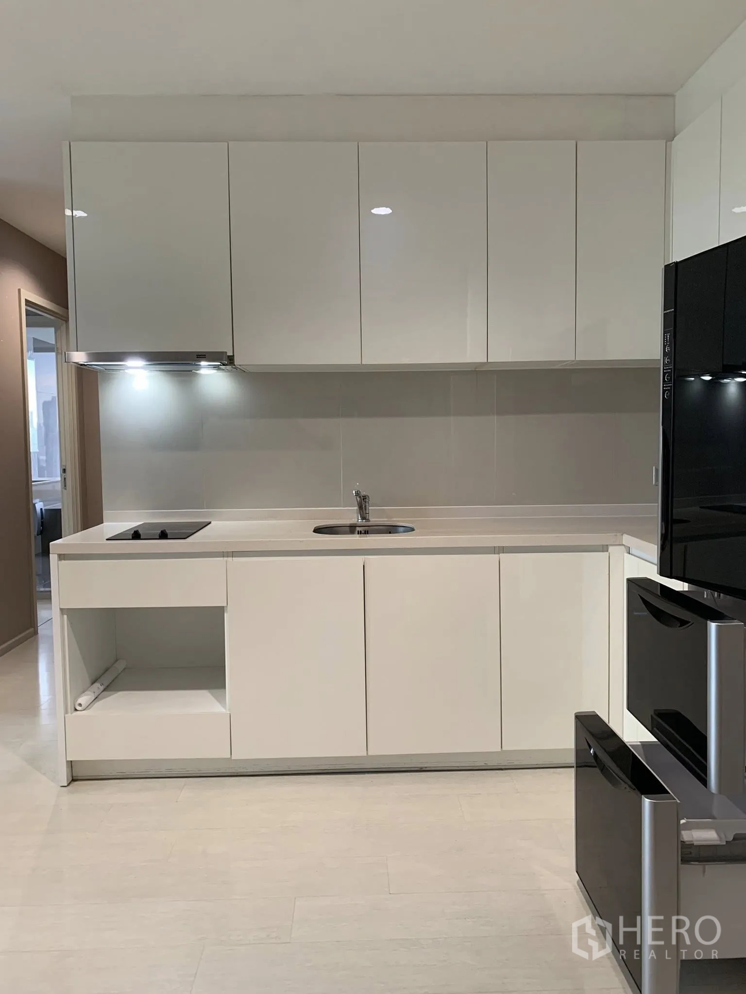 คอนโด for rent in Khlong Toei, Bangkok - ครัวโทนสีขาวพร้อมตู้เก็บของ เตา เครื่องดูดควัน และพื้นที่เตรียมอาหาร