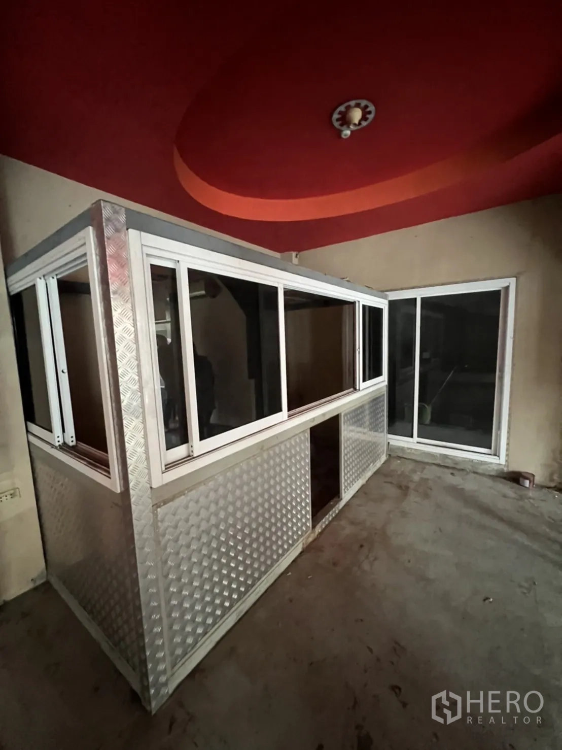 Shophouse for rent in Watthana, Bangkok - Wide floor with grid ceiling, glass partitions and checker-plate wrapped columns.