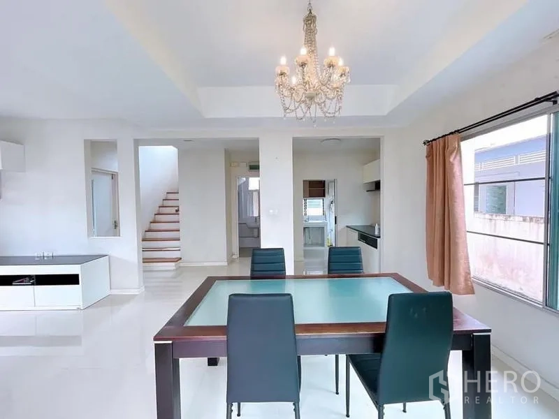 บ้าน ให้เช่าในBang Na, Bangkok - มุมรับประทานอาหารโปร่งพร้อมโคมระย้าและผนังสีขาวใกล้บันได