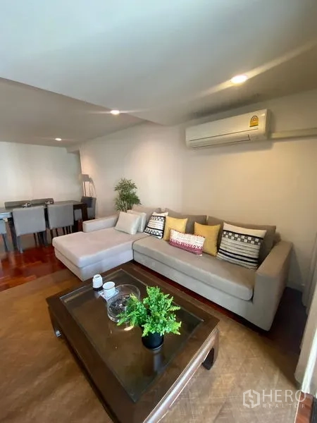 公寓 出租在Pathum Wan, Bangkok - 明亮客厅，转角沙发与空调。