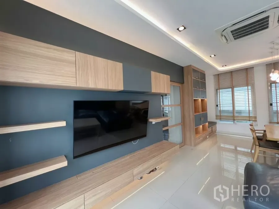 Detached House for rent or sale in Khlong Luang, Pathum Thani - Modern living room with built-in wood TV wall, cabinets and shelves.