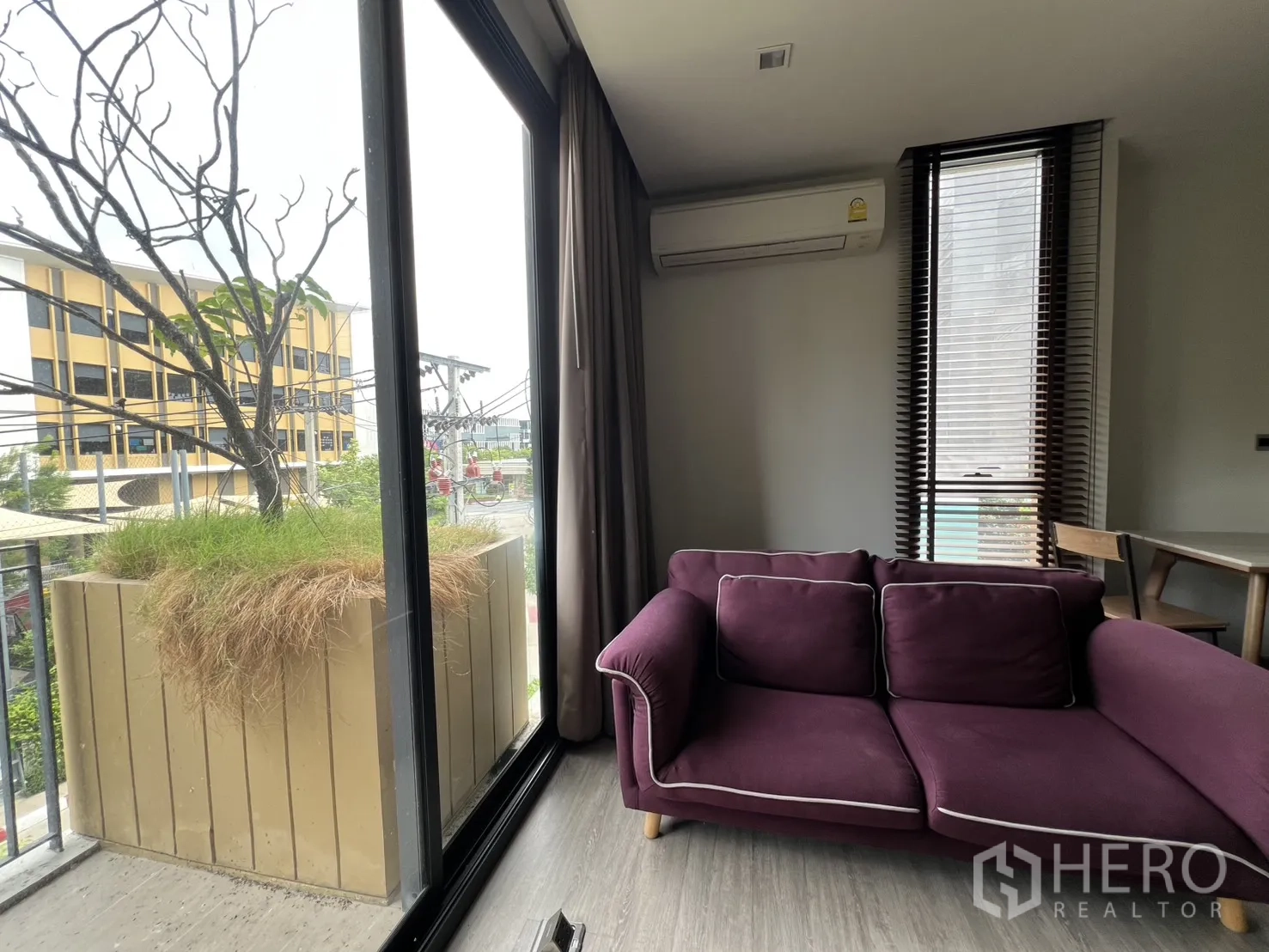 คอนโด for rent in Watthana, Bangkok - มุมห้องนั่งเล่นกับประตูบานเลื่อนบานใหญ่และโซฟาสีม่วงข้างหน้าต่าง