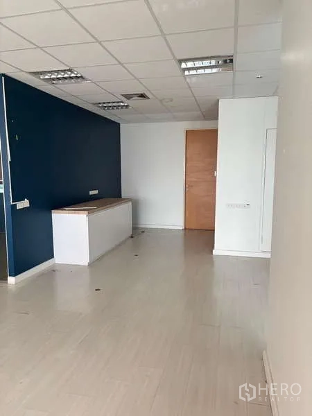 Office Space for rent in Bang Na, Bangkok - Office corner with blue accent wall, ceiling lights and a wooden door.