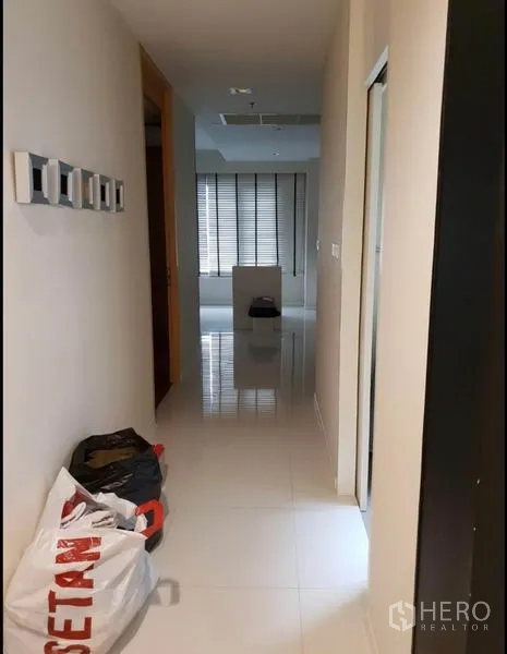 Condominium for rent in Sathon, Bangkok - Bright corridor with glossy floors leading toward a windowed living area.