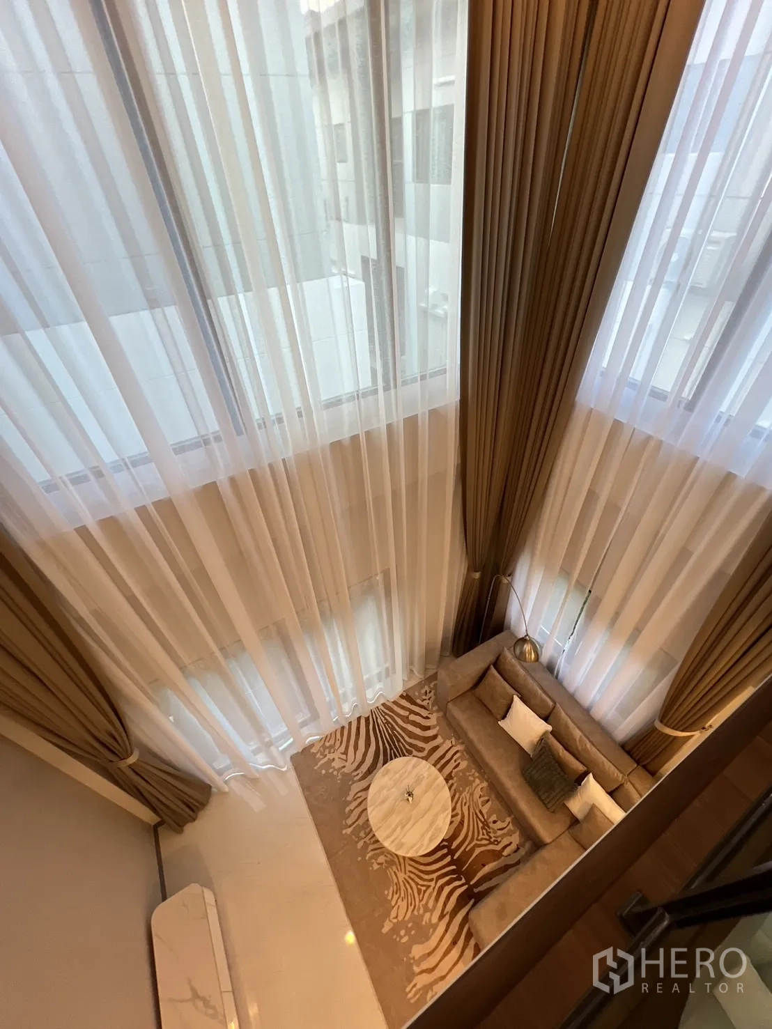 Detached House for rent or sale in Bang Phli, Samut Prakan - Bird’s-eye view from mezzanine over living room with round coffee table and rug.