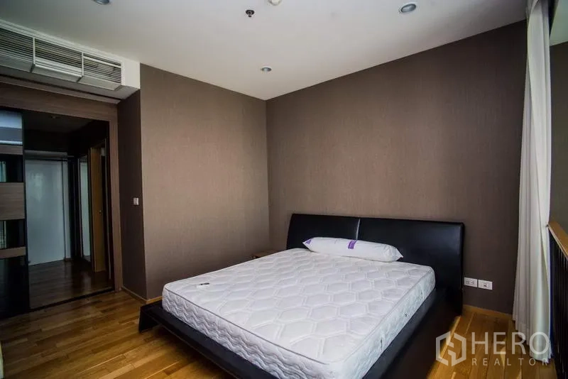 Condominium for rent or sale in Khlong Toei, Bangkok - Cozy bedroom with wood floors, recessed lighting, and built-in air conditioning.