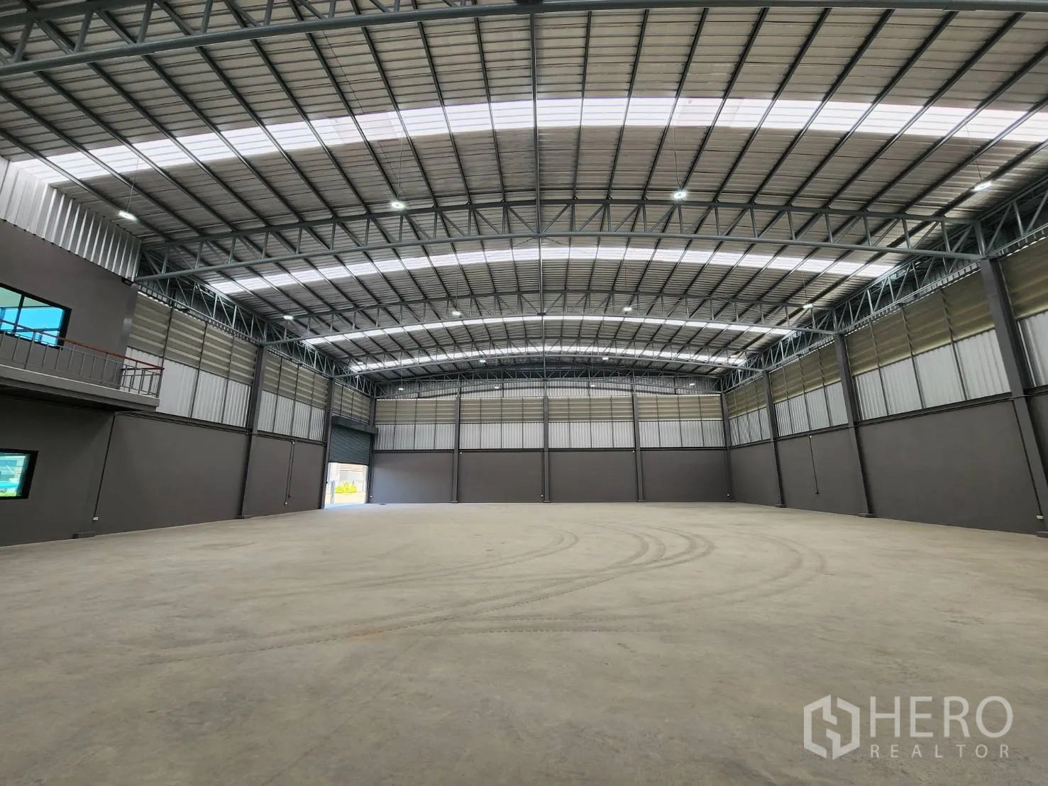 Factory for rent or sale in Bang Sao Thong, Samut Prakan - Spacious clear-span warehouse interior with high steel truss roof, skylight panels, and polished concrete floor.
