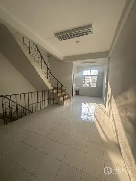 Shophouse for rent in Khlong Toei, Bangkok - Bright tiled landing with metal staircase and sunlit window in a shophouse.