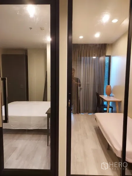 Condominium for rent in Phaya Thai, Bangkok - Glass sliding partitions separating bedroom and a study/daybed area with curtains.