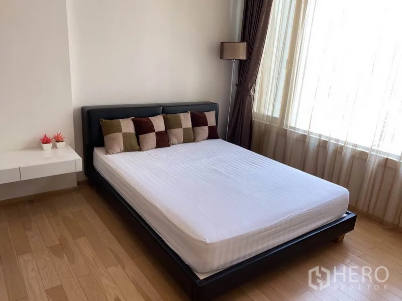 Condominium for rent in Khlong Toei, Bangkok - Sunlit bedroom with large window, queen bed and wooden floors.