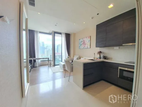 公寓 出租或出售在Watthana, Bangkok - 利落的半岛台厨房与吊柜，面向采光明亮且连通阳台的客厅。