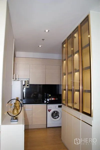 Condominium for sale - Galley kitchen with gold-framed glass cabinets, fridge, microwave and washer.