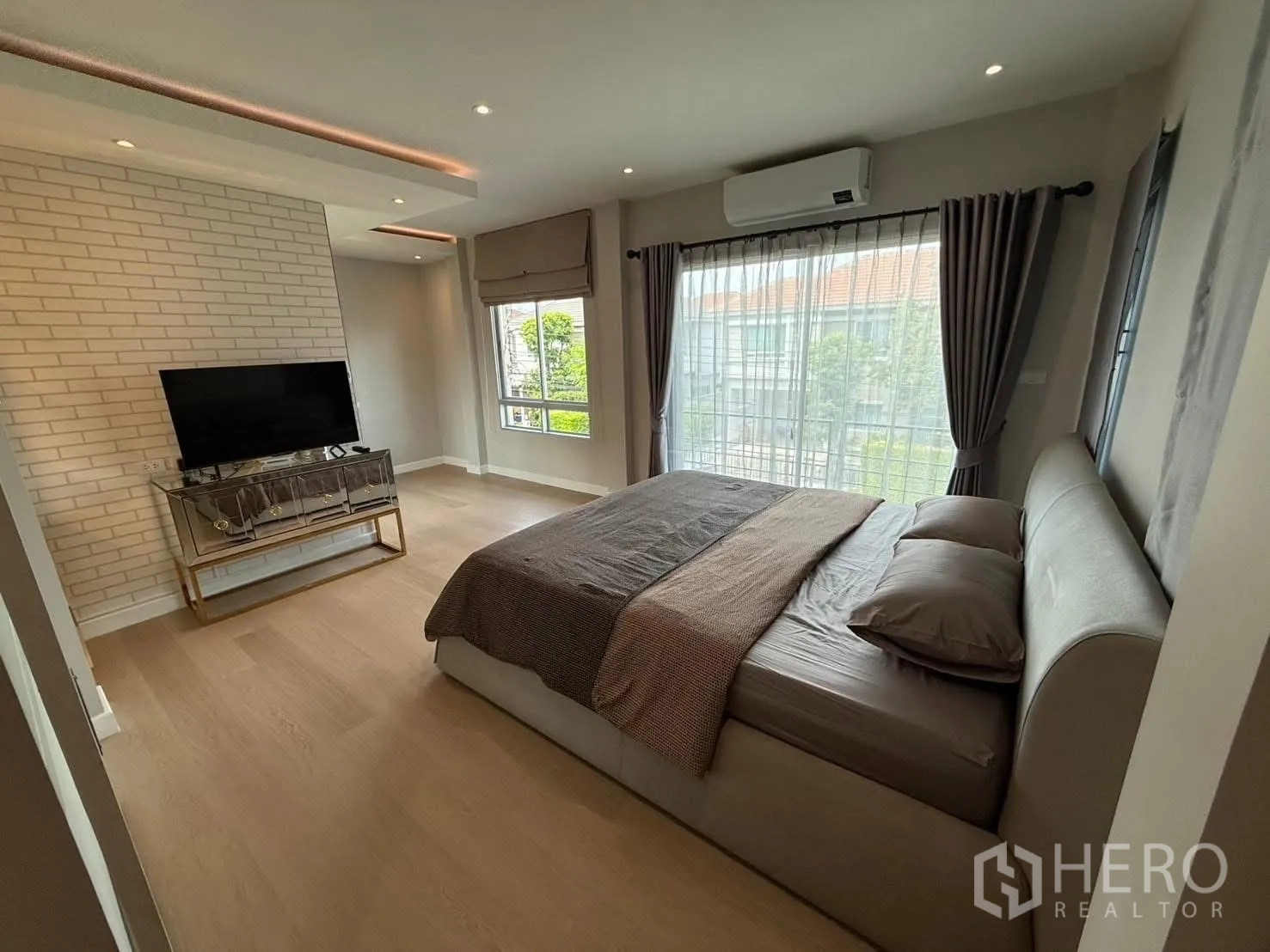 独栋房屋 for rent in Prawet, Bangkok - 采光充足的主卧，配大床、电视柜、砖纹特色墙、落地窗与空调