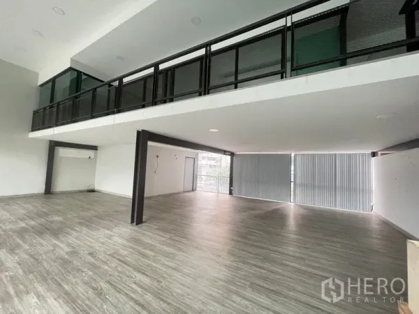 办公空间 出租在Bang Na, Bangkok - 夹层下方开放式楼层，大窗与竖百叶，木纹地面。