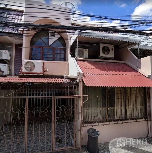 联排别墅 出租在Khlong Toei, Bangkok - 两层联排别墅外立面，带金属大门、遮棚和外置空调机组