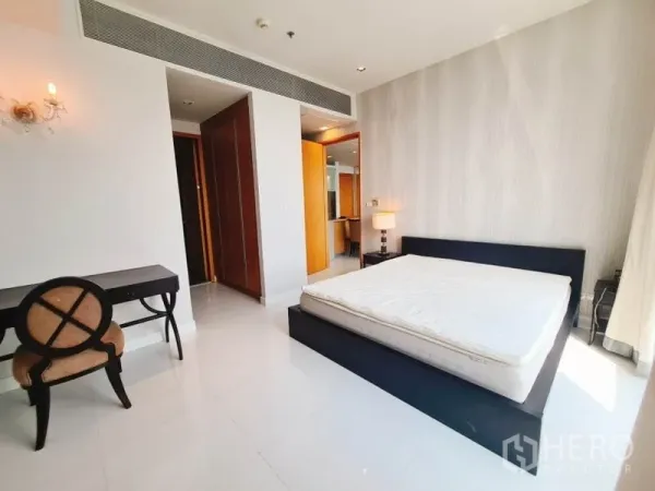 Condominium for rent in Khlong Toei, Bangkok - Spacious bedroom with platform bed, writing desk, built-in wardrobe and soft bedside lighting.
