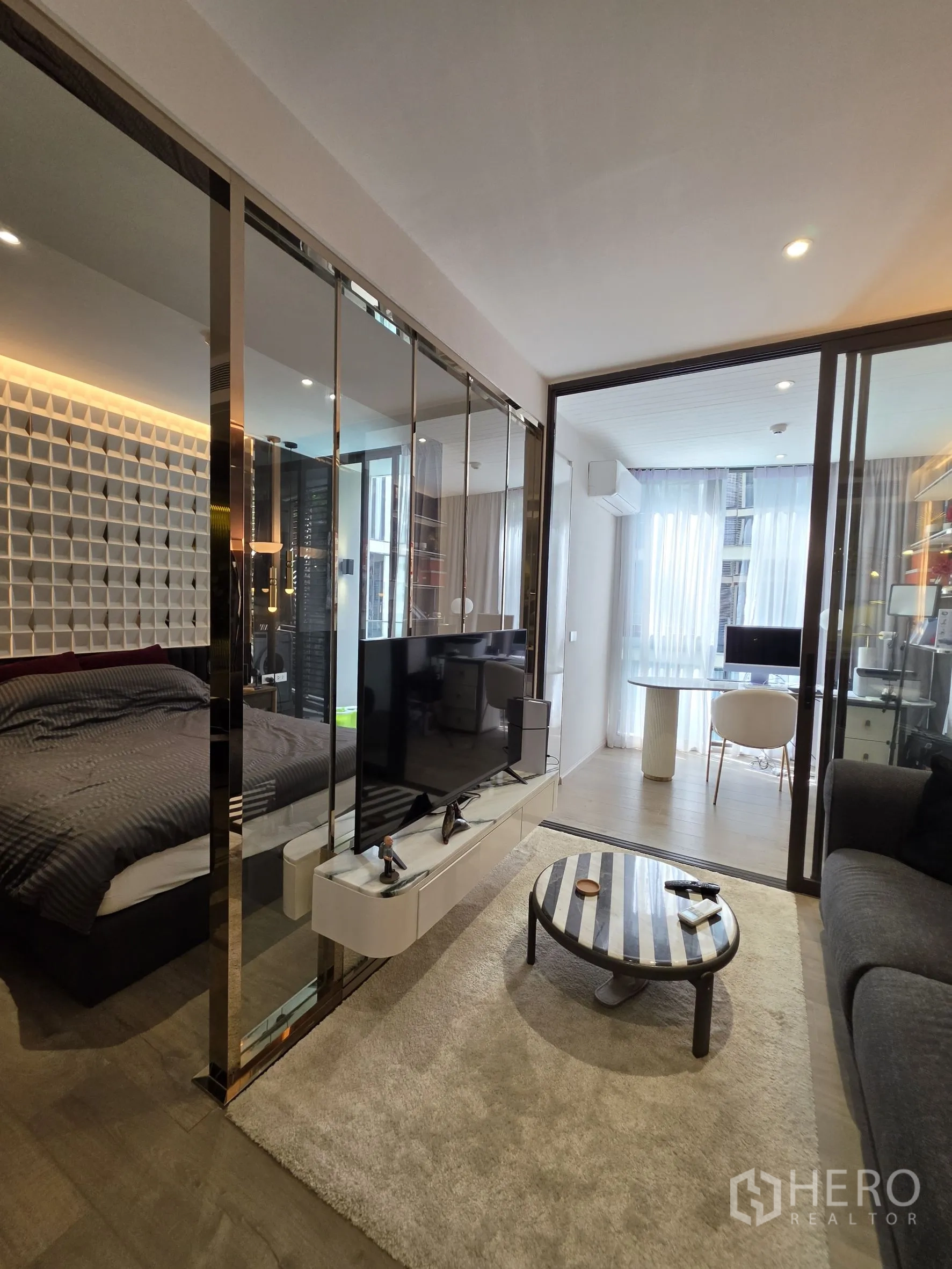 公寓 for rent in Khlong Toei, Bangkok - 开放式客厅设沙发与电视柜，玻璃隔断连接卧室，尽头为明亮用餐区。