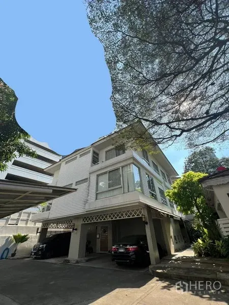 Townhouse for rent in Khlong Toei, Bangkok - Three-storey townhouse exterior with covered parking beneath mature trees in Sukhumvit.