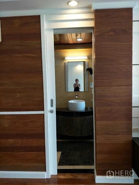 公寓 出租或出售在Watthana, Bangkok - 木饰面墙之间的推拉门，通往主卧套间浴室。