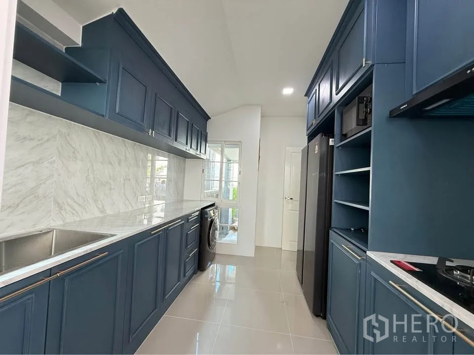 Semi-detached House for rent in Mueang Samut Prakan, Samut Prakan - Kitchen from opposite angle showing tall cabinets, refrigerator space, and washing machine.