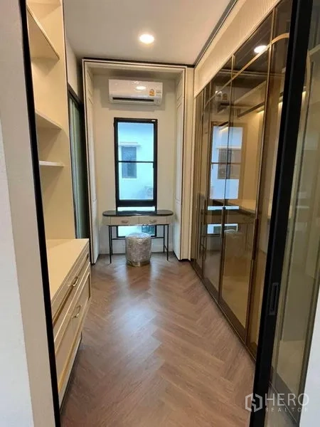 Detached House for rent in Saphan Sung, Bangkok - Slim walk-in closet with glass wardrobes, built-in drawers and a study desk.