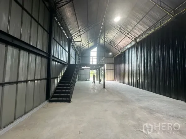 Warehouse for rent in Bueng Kum, Bangkok - Long aisle view of the warehouse showing stairs to a mezzanine and clerestory windows.