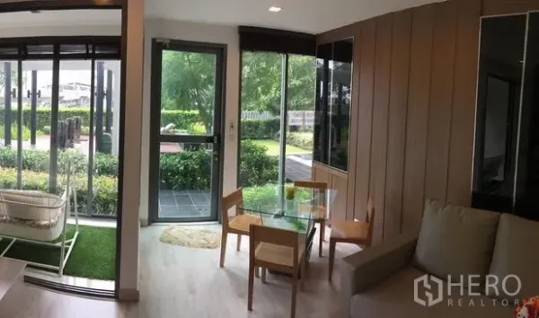 Condominium for rent in Phra Khanong, Bangkok - Bright living and dining area with glass doors opening to a garden-side terrace.