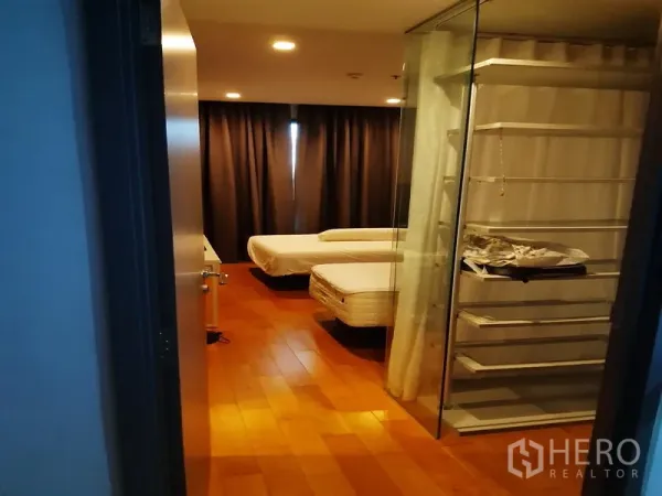 Condominium for rent or sale in Khlong Toei, Bangkok - Spacious bedroom with walk-in glass wardrobe and wood floors.