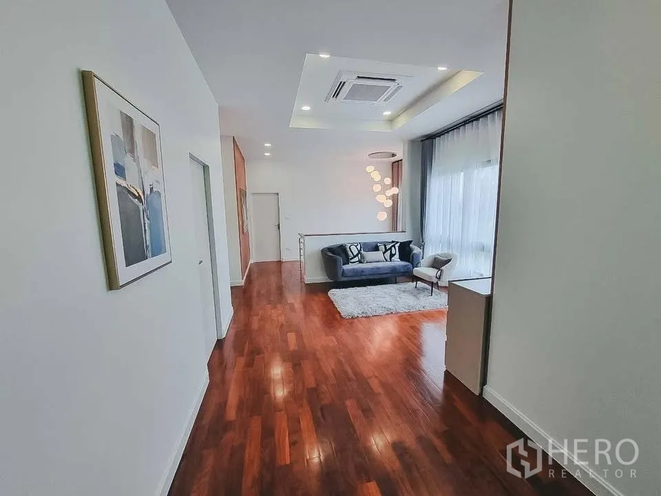 独栋房屋 for rent or sale in Bang Phli, Samut Prakan - 宽敞的楼层休闲区，木地板与筒灯，小型沙发组。