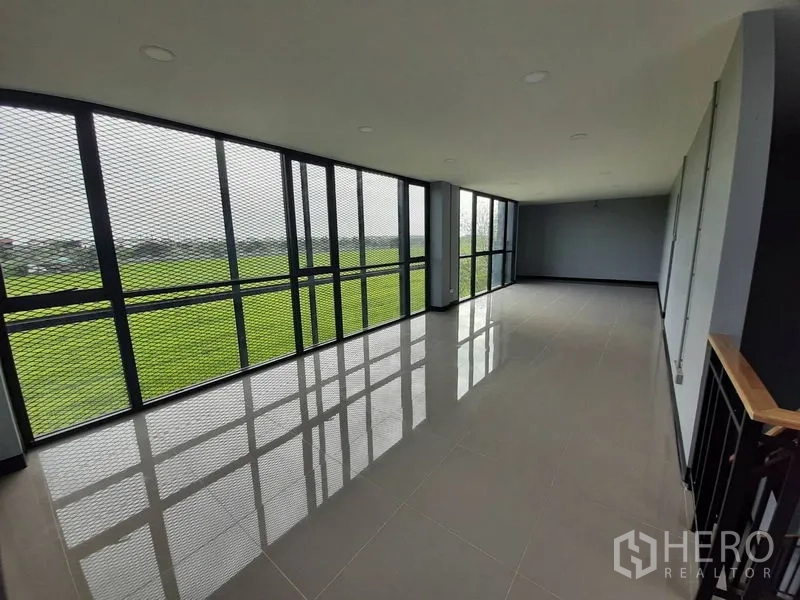 Factory for rent or sale in Lam Luk Ka, Pathum Thani - Long glazed office space with mesh sunshade overlooking green fields.