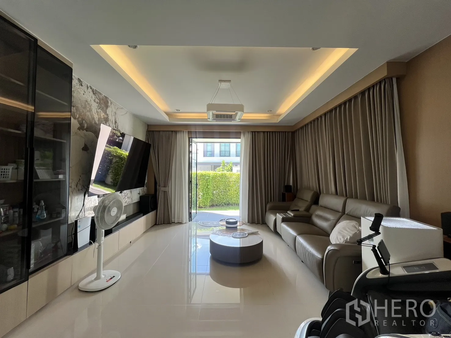 独立式住宅 出租或出售在Mueang Pathum Thani, Pathum Thani - 现代客厅，大沙发、电视背景墙与落地推门。