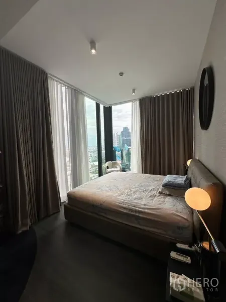 Condominium for rent in Bang Rak, Bangkok - Corner bedroom with floor-to-ceiling windows, bedside lamps, and expansive Bangkok city views.