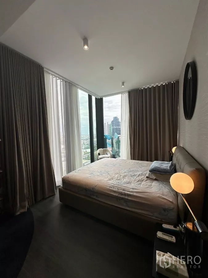 Condominium for rent in Bang Rak, Bangkok - Corner bedroom with floor-to-ceiling windows, bedside lamps, and expansive Bangkok city views.
