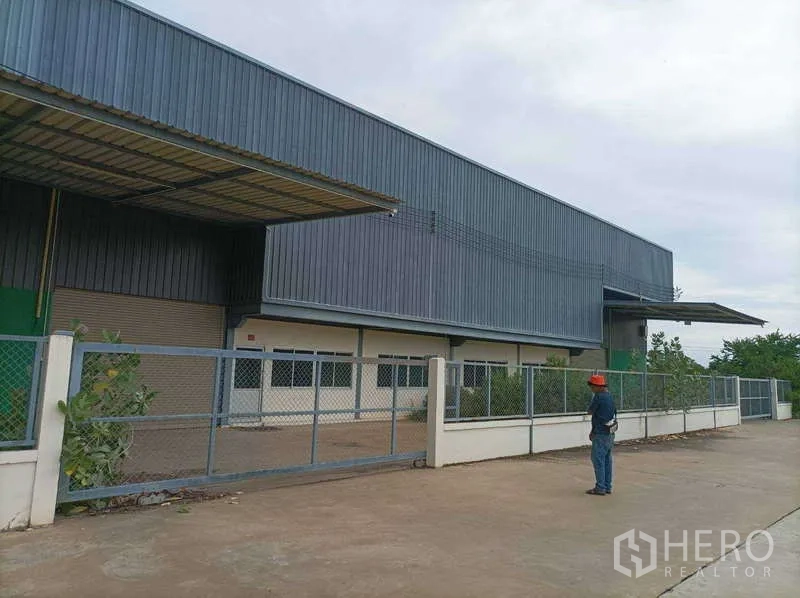 工厂 for rent in Ban Phaeo, Samut Sakhon - 仓库正面带金属大门、雨棚与卷闸装卸口。